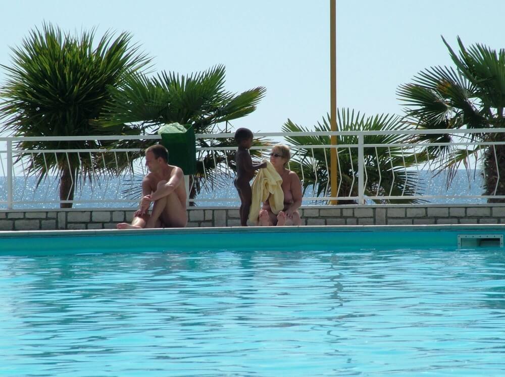 Photo of naturists in an outdoor pool - Nature serves as the bodys natural clothing